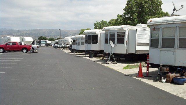 A row of trailers are parked in a parking lot