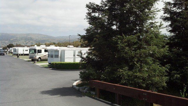 A row of rvs parked in a parking lot with mountains in the background