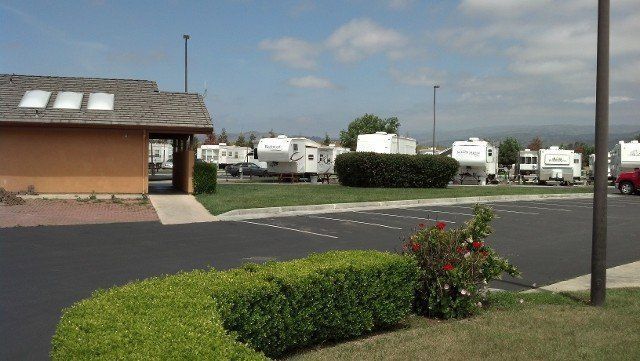 A row of rvs are parked in a parking lot next to a building.