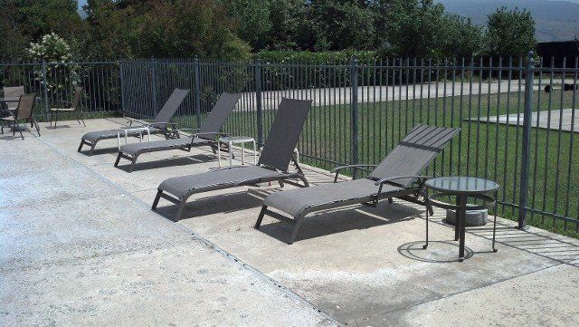 A row of lounge chairs are lined up in front of a pool