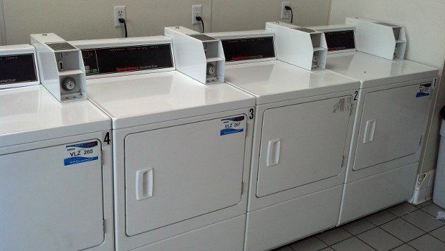 A row of white washers and dryers in a laundromat