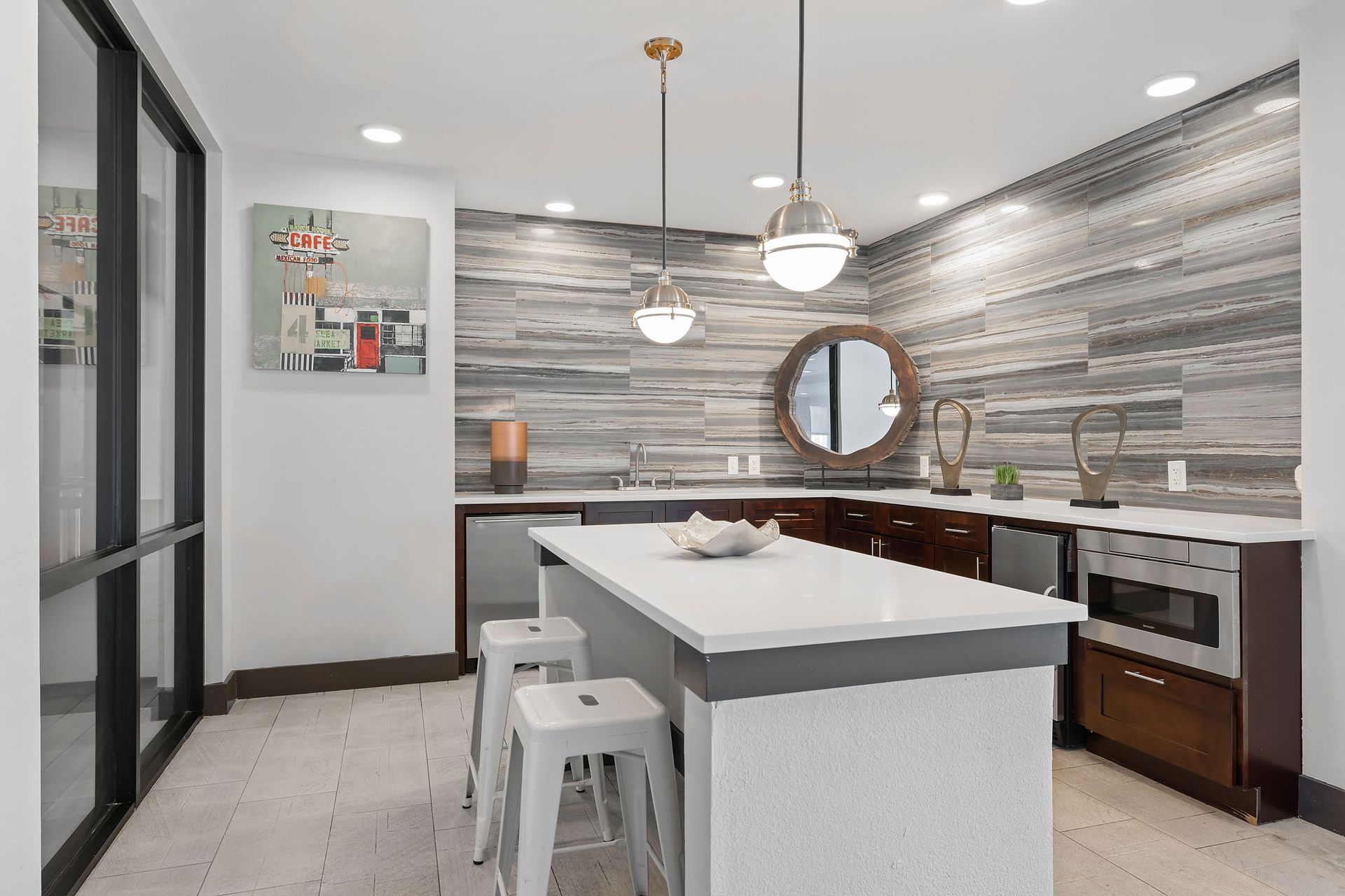 There is a large island in the middle of the kitchen with a modern backsplash and designer lighting at The Heights apartments near SHSU in Huntsville, TX.