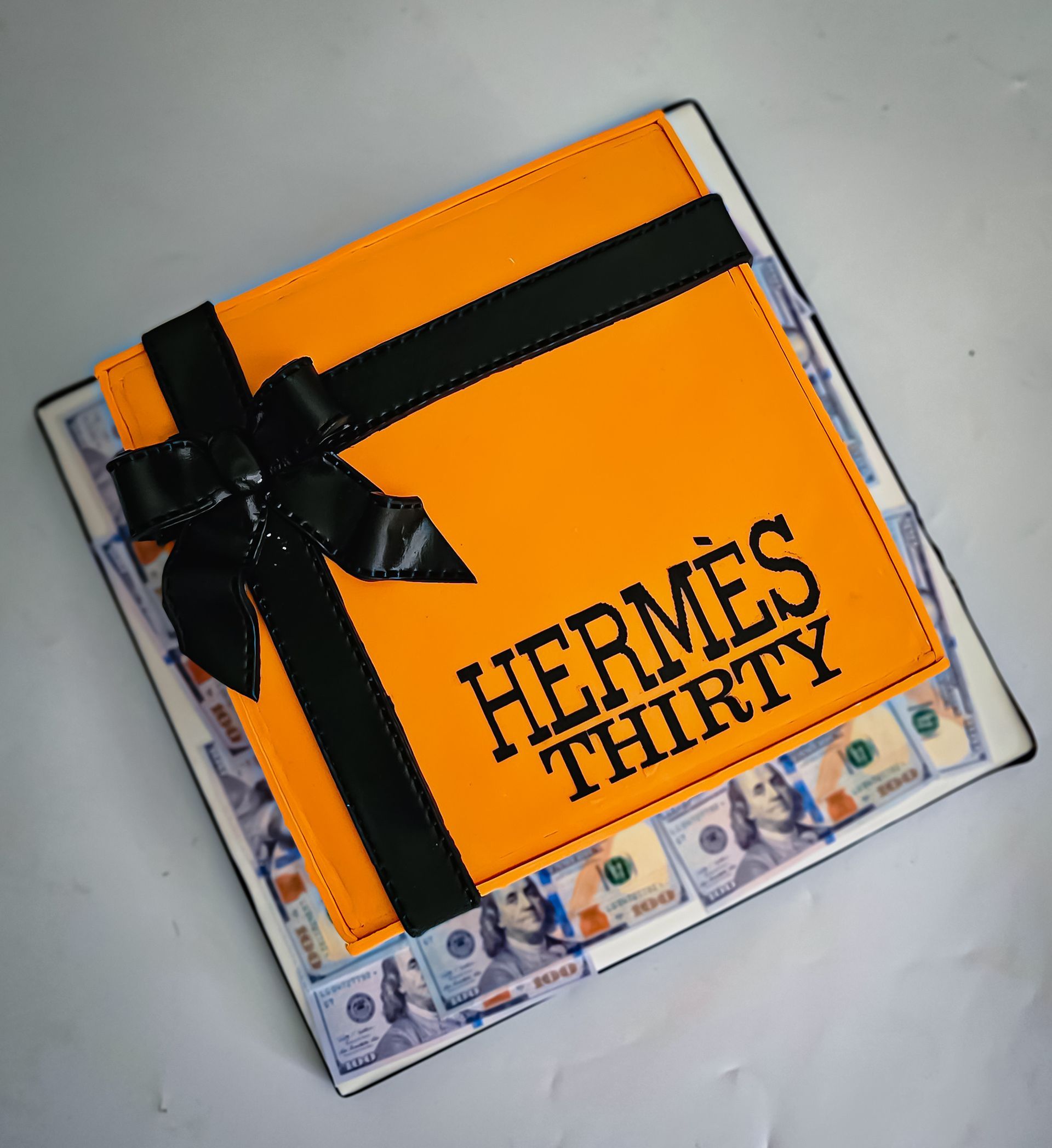 Cake decorated as an Hermes gift box in orange with a black bow,