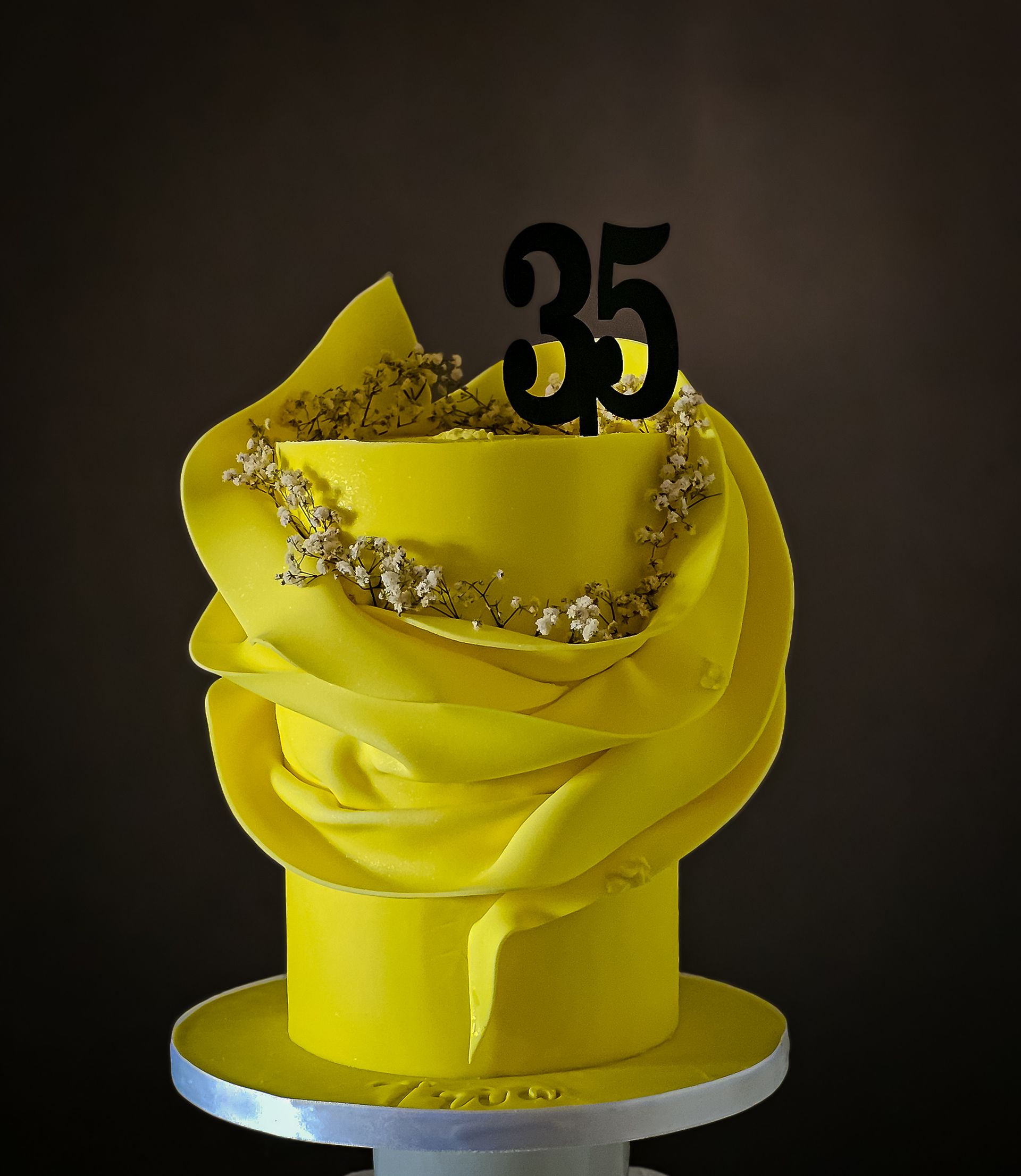 Yellow birthday cake with the number 35 on top, with decorative yellow fondant and golden accents.