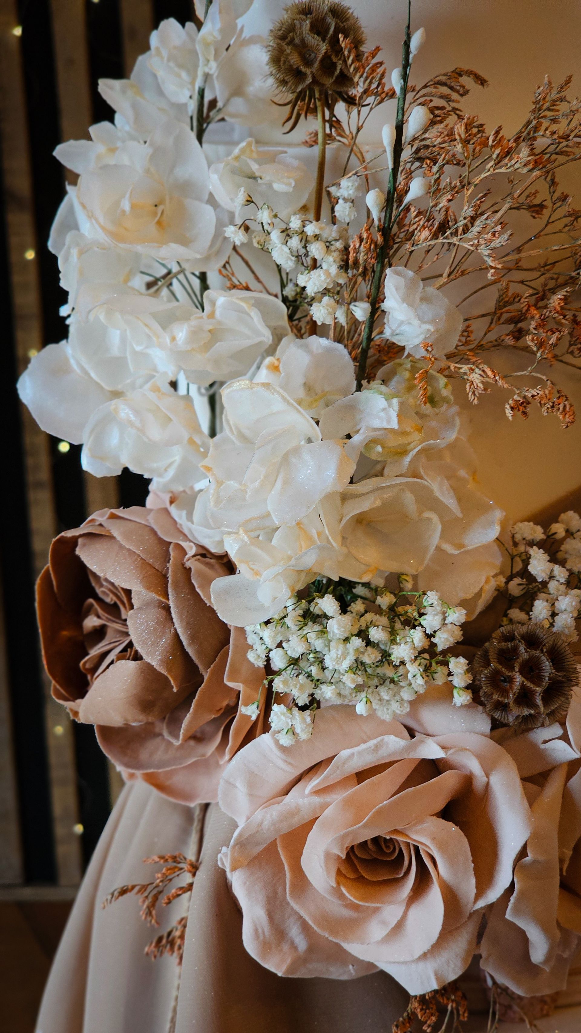 Close-up of a floral arrangement with cream and blush-toned flowers, including roses and hydrangeas.