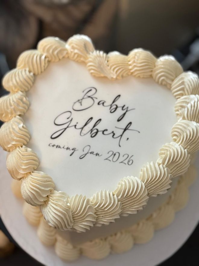Heart-shaped cake with piped frosting border. Text on top reads 