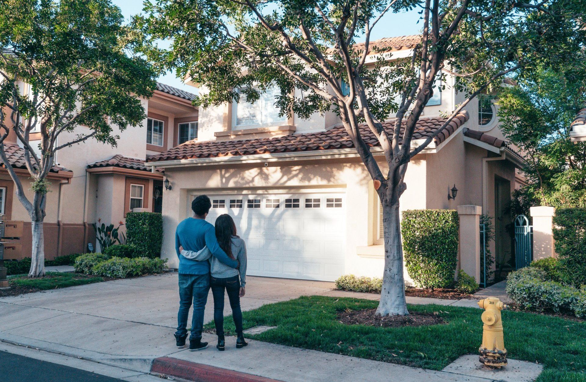 A man and a woman are standing in front of a house.