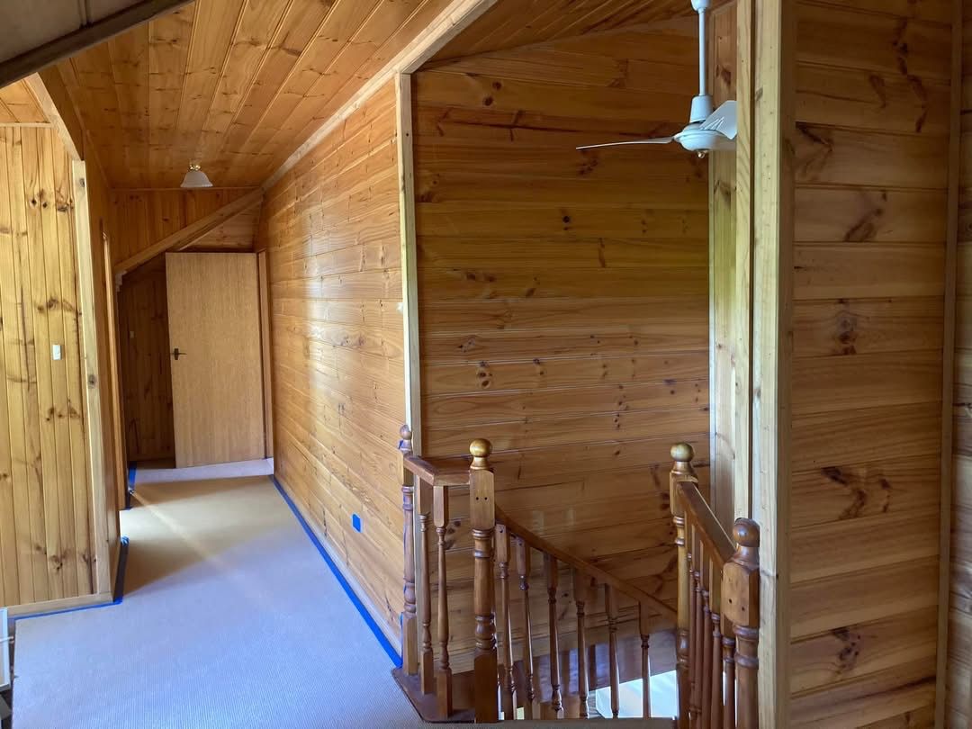 Wooden interior with staircase, ceiling fan, and hallway with a closed door.