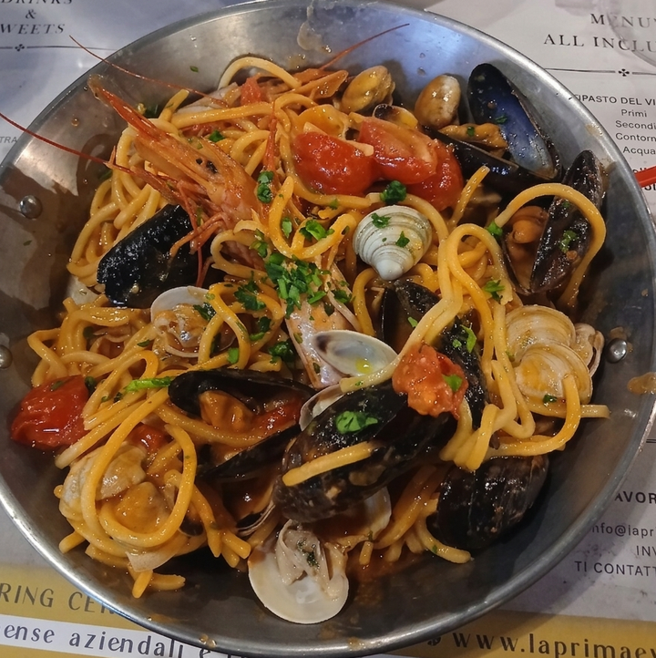 Un piatto di spaghetti con cozze, vongole e pomodorini in salsa di mare.