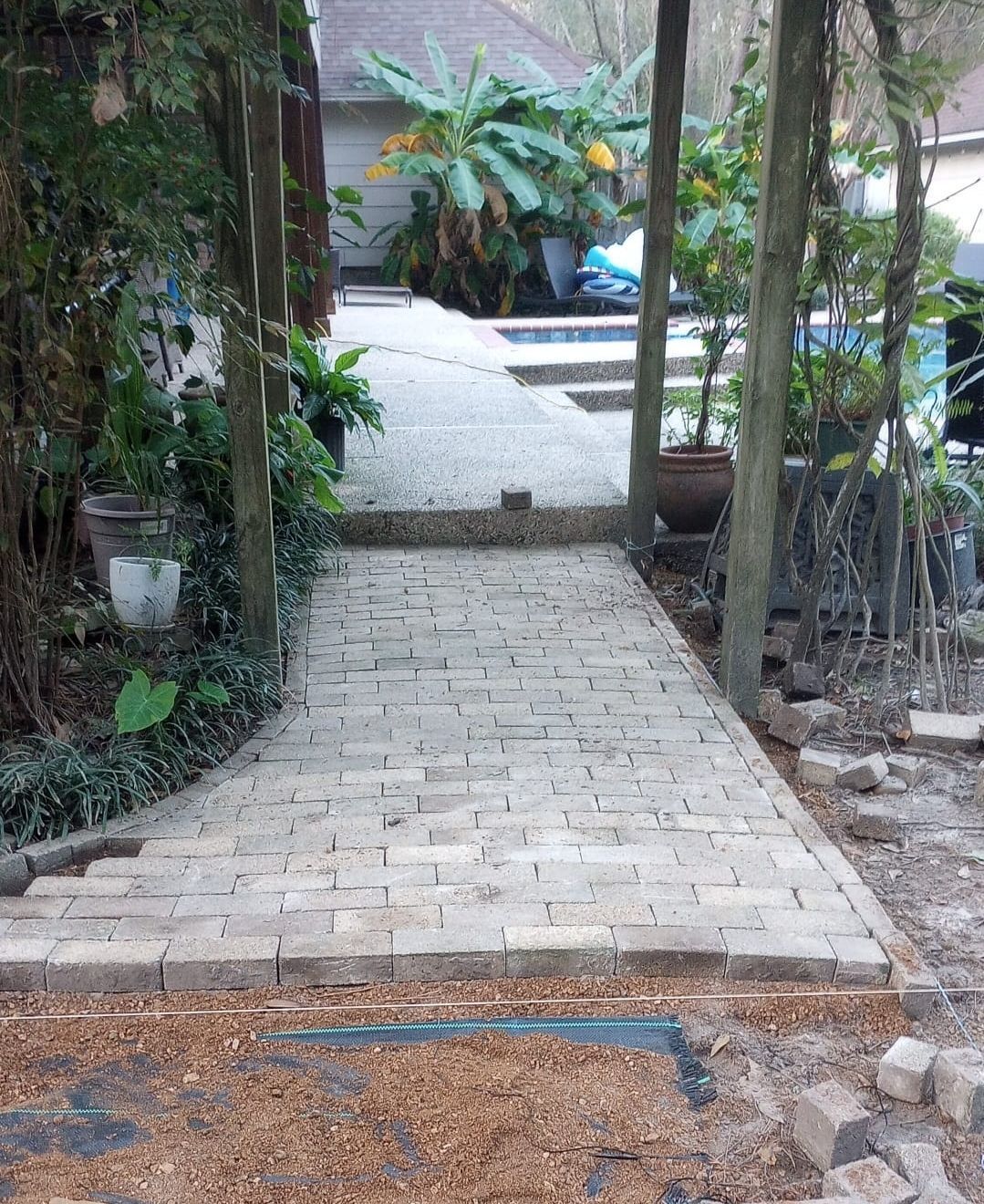 Brick pathway leading up steps through a shaded garden area with trees and plants