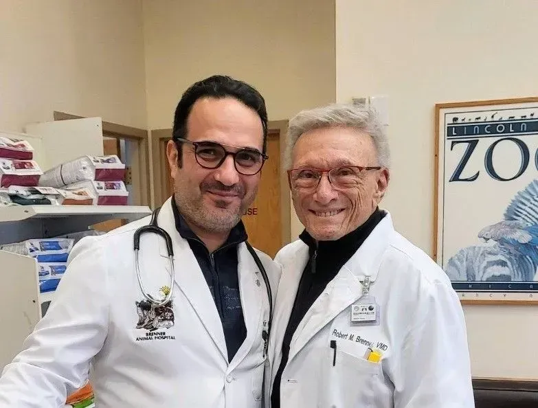 Two doctors are posing for a picture in front of a zoo poster