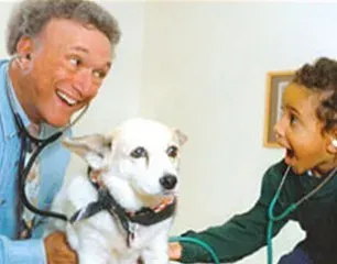 A man and a child are examining a dog with a stethoscope.