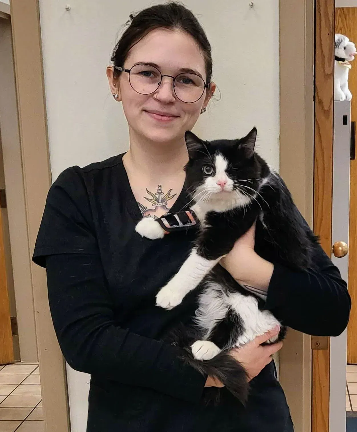 A woman is holding a black and white cat in her arms.