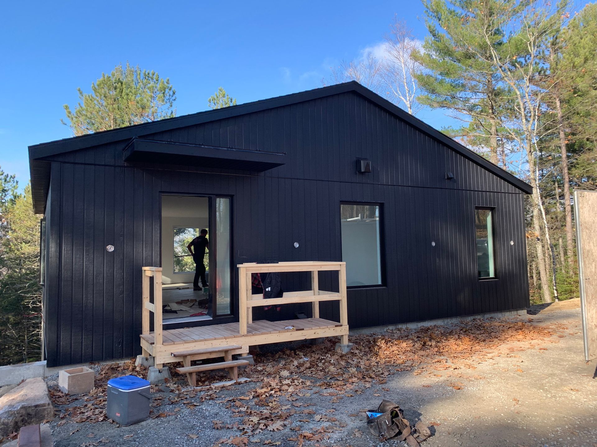 Une petite maison noire est en construction dans les bois.