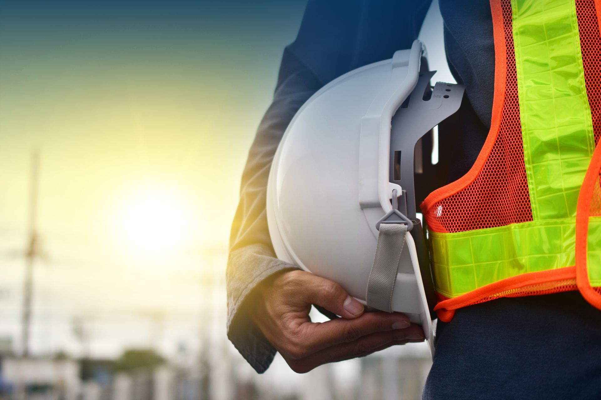Un ouvrier du bâtiment tient un casque de chantier dans sa main.