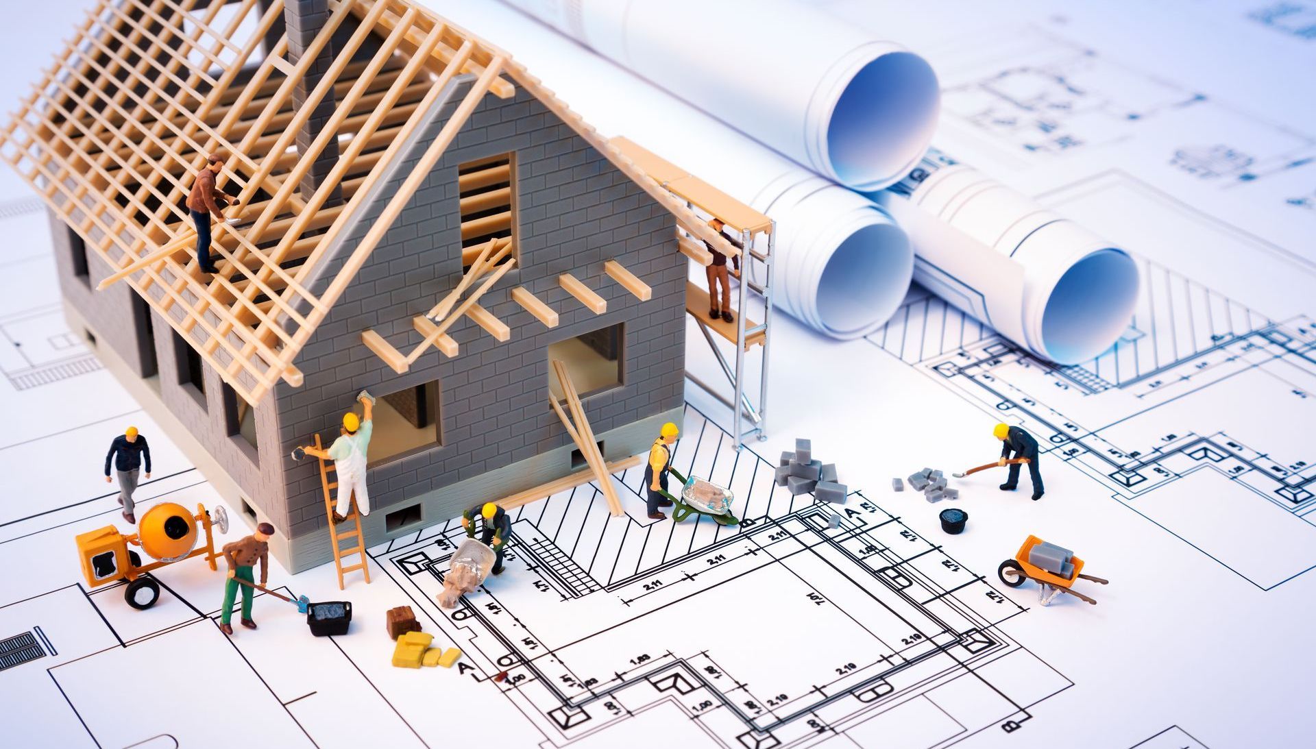 Une maison modèle est en cours de construction sur un plan.