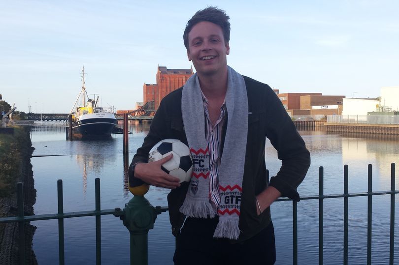 A man holding a soccer ball in front of a body of water