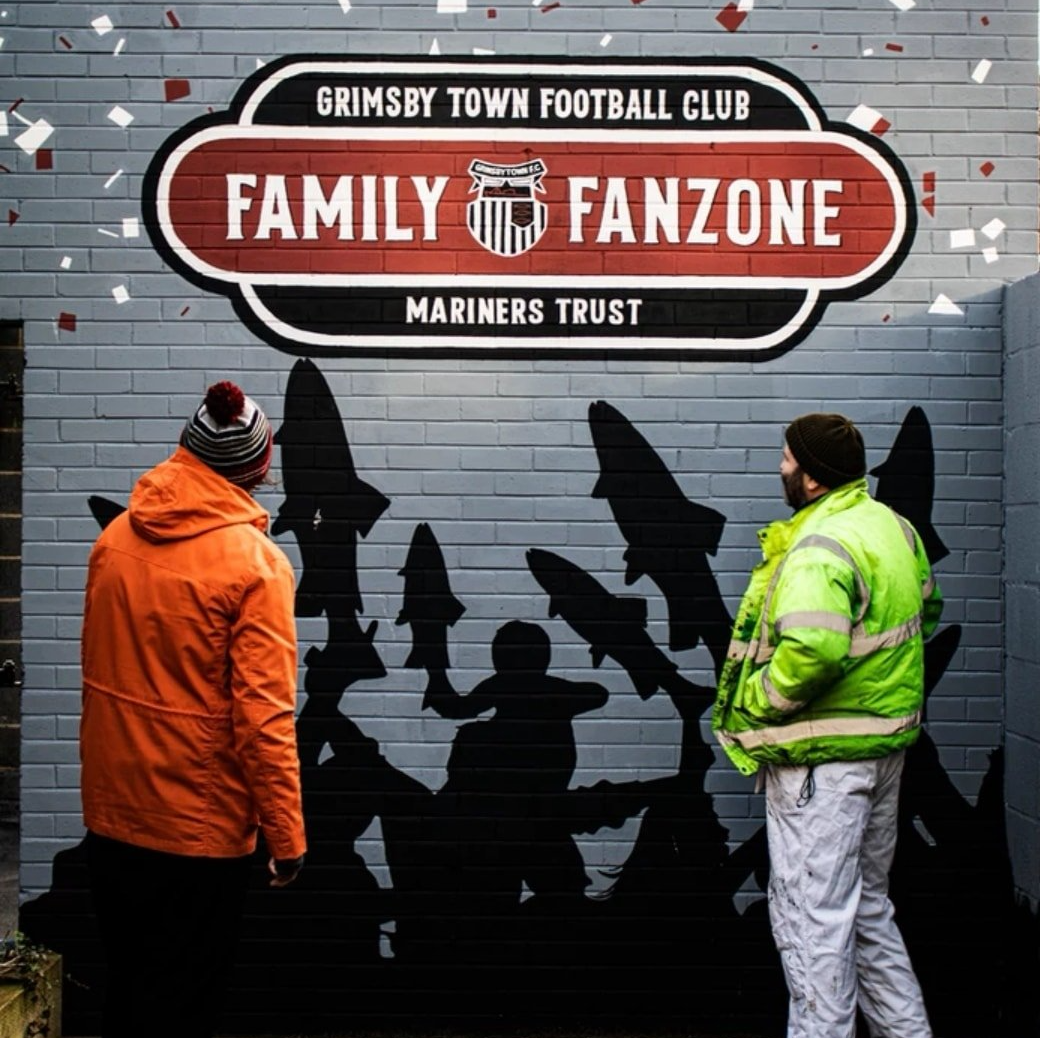 Two men standing in front of a sign that says family fanzone