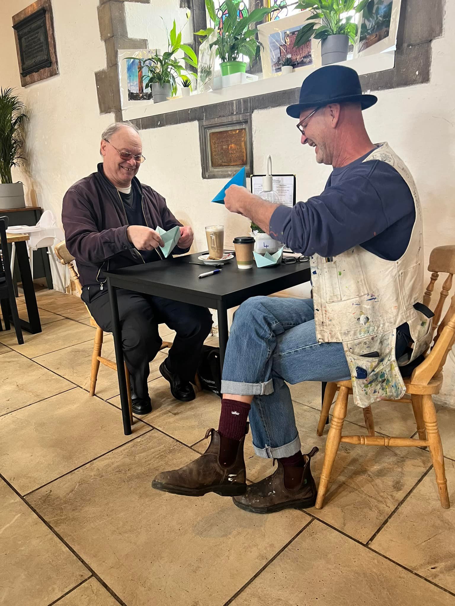Two men are sitting at a table in a restaurant playing cards.