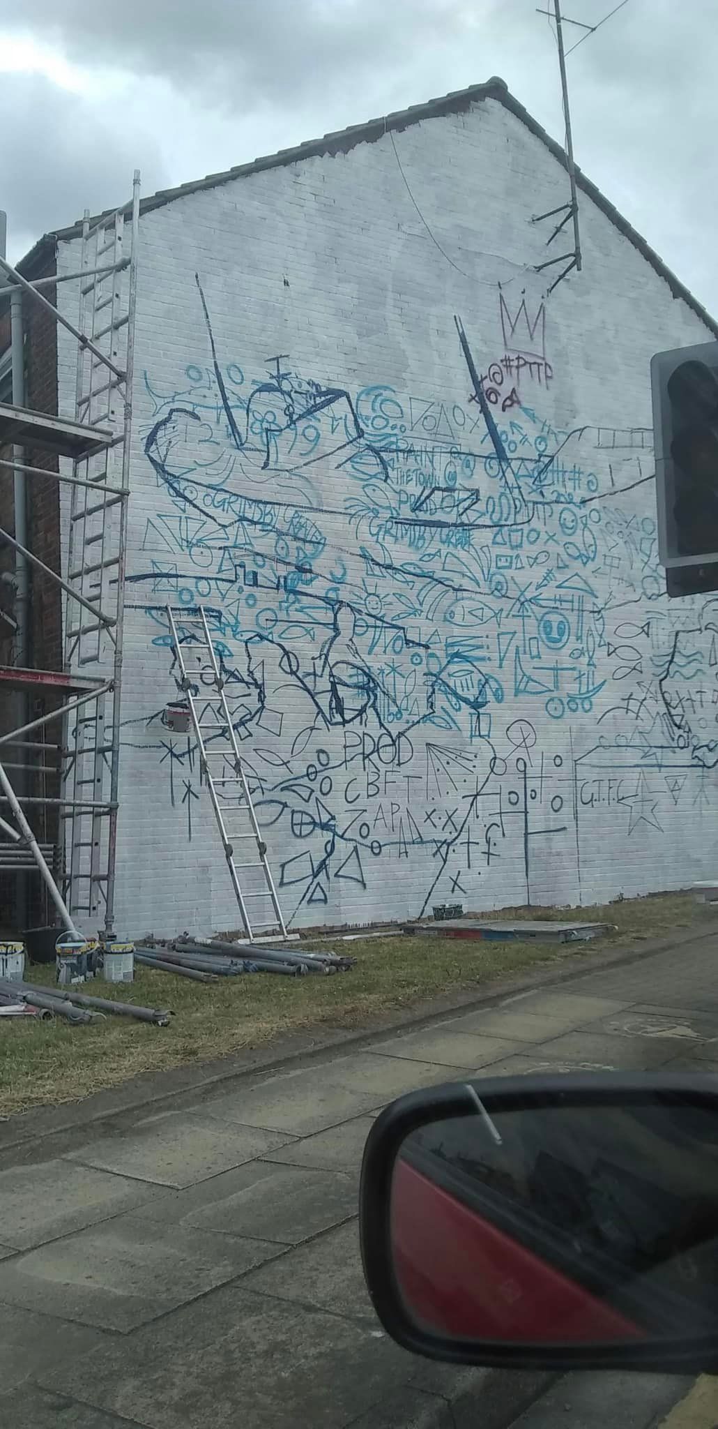 A white building with graffiti on it is being painted.