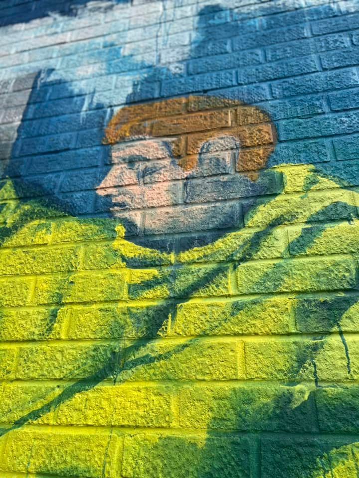 A painting of a man 's face on a brick wall.
