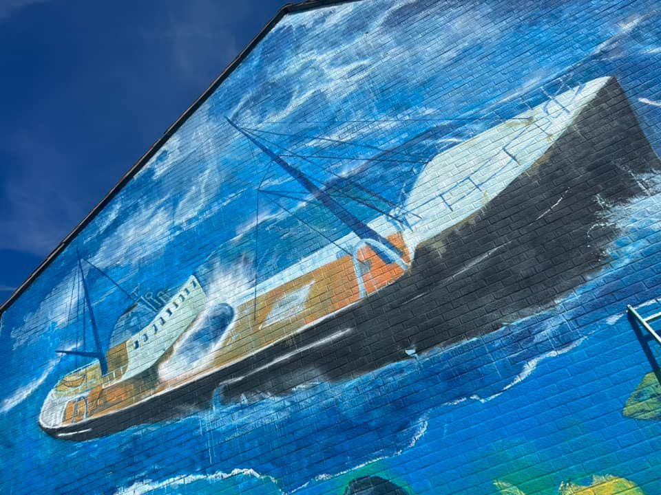 A large painting of a ship in the ocean on the side of a building.
