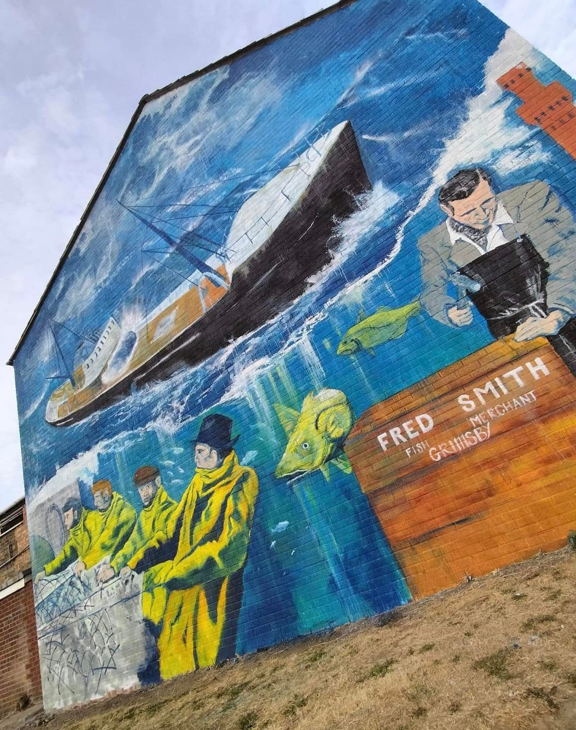 A large mural on the side of a building shows a ship in the ocean.