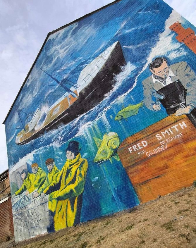 A large mural on the side of a building shows a ship in the ocean.