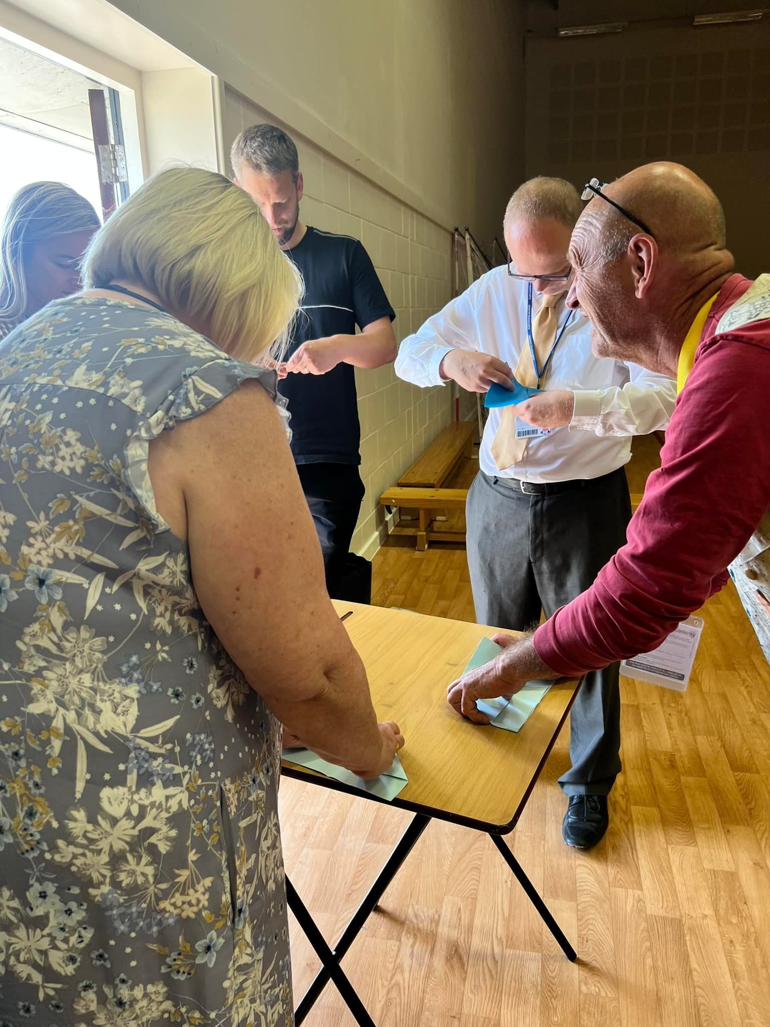 A group of people are standing around a table.