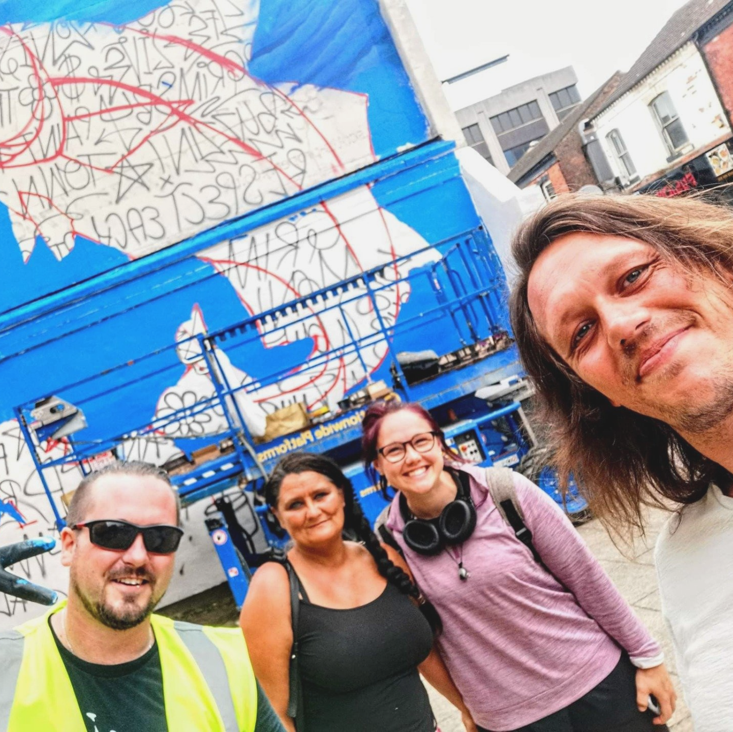 A group of people posing for a picture in front of the mural.