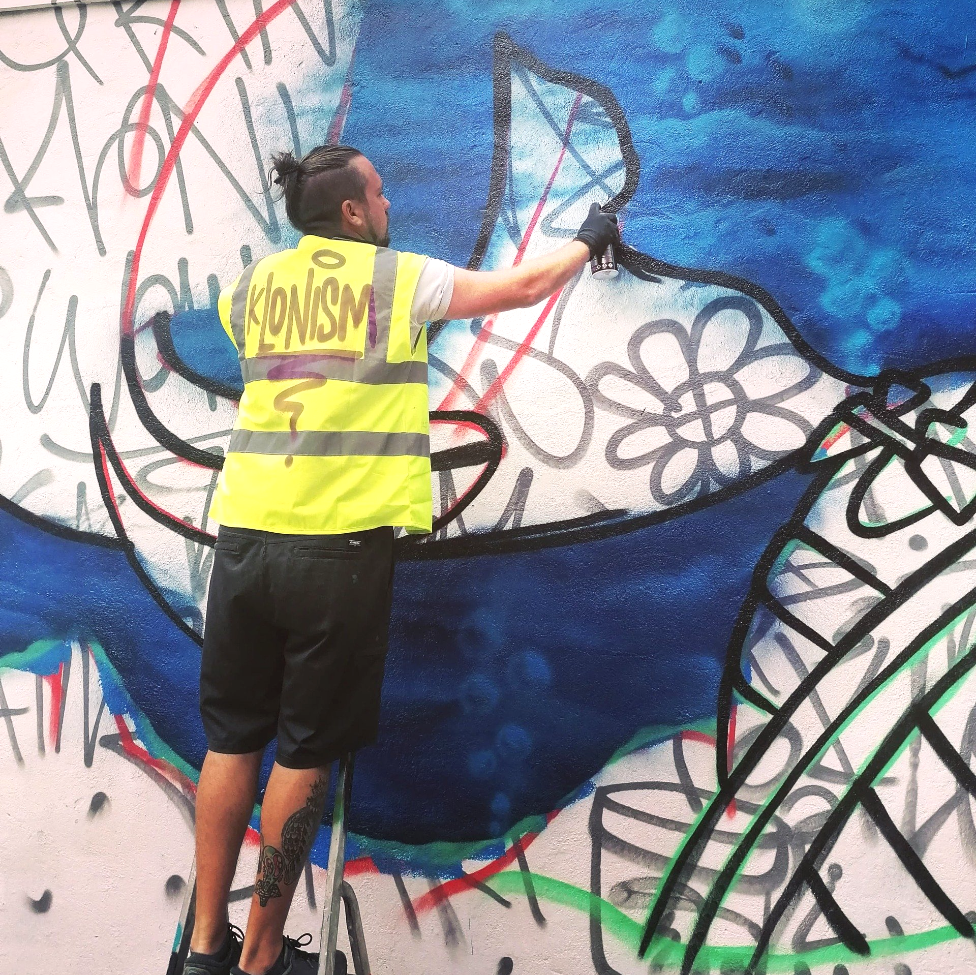 A man wearing a yellow vest with the word Klonism on it.