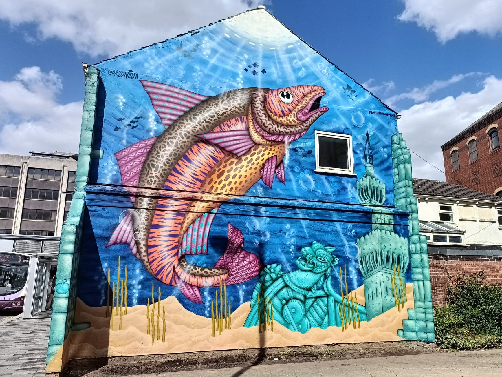 A colorful mural of a fish on the side of a building.