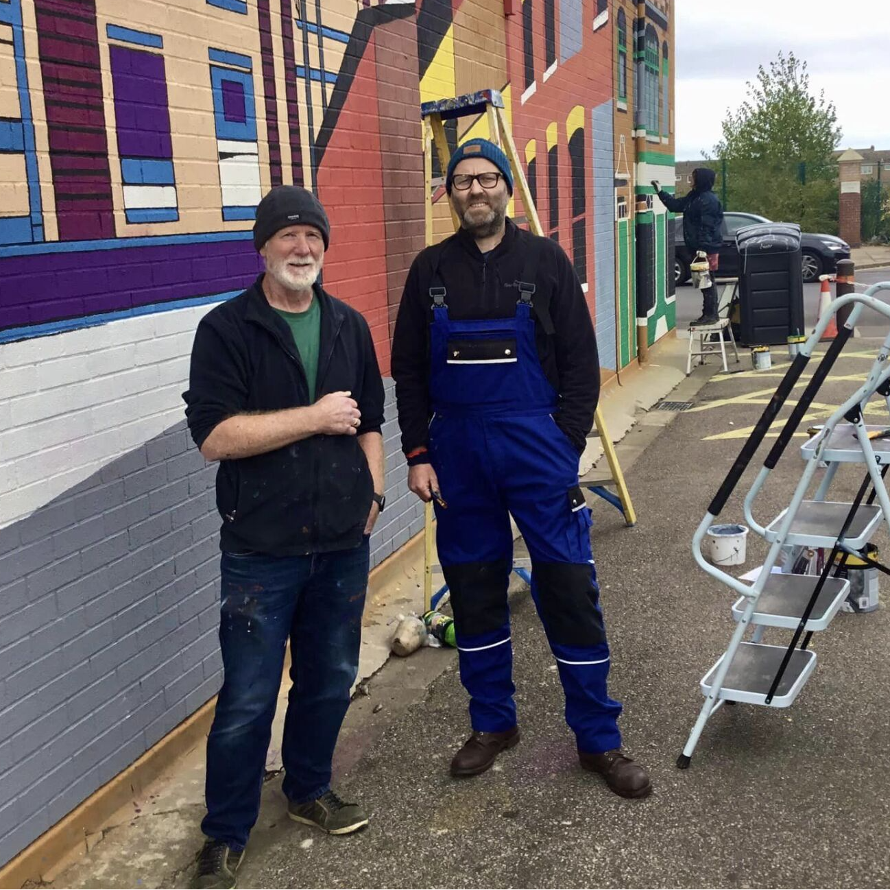 Two men standing next to each other in front of a building