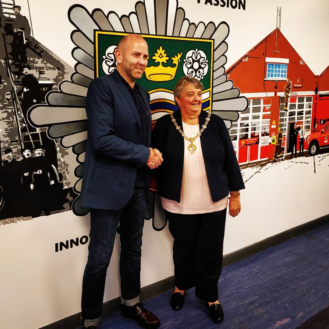 A man and woman shaking hands in front of a mural