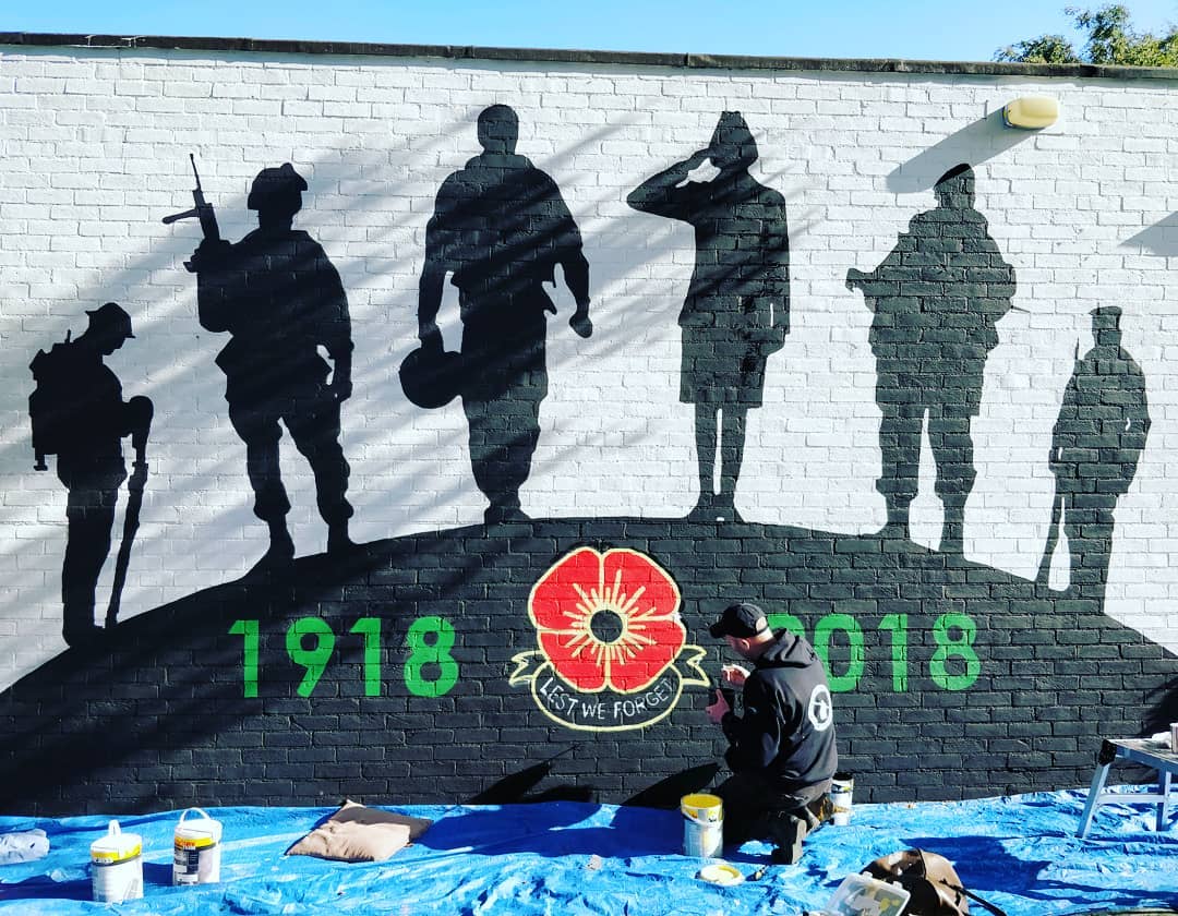 A mural of soldiers is being painted on a brick wall