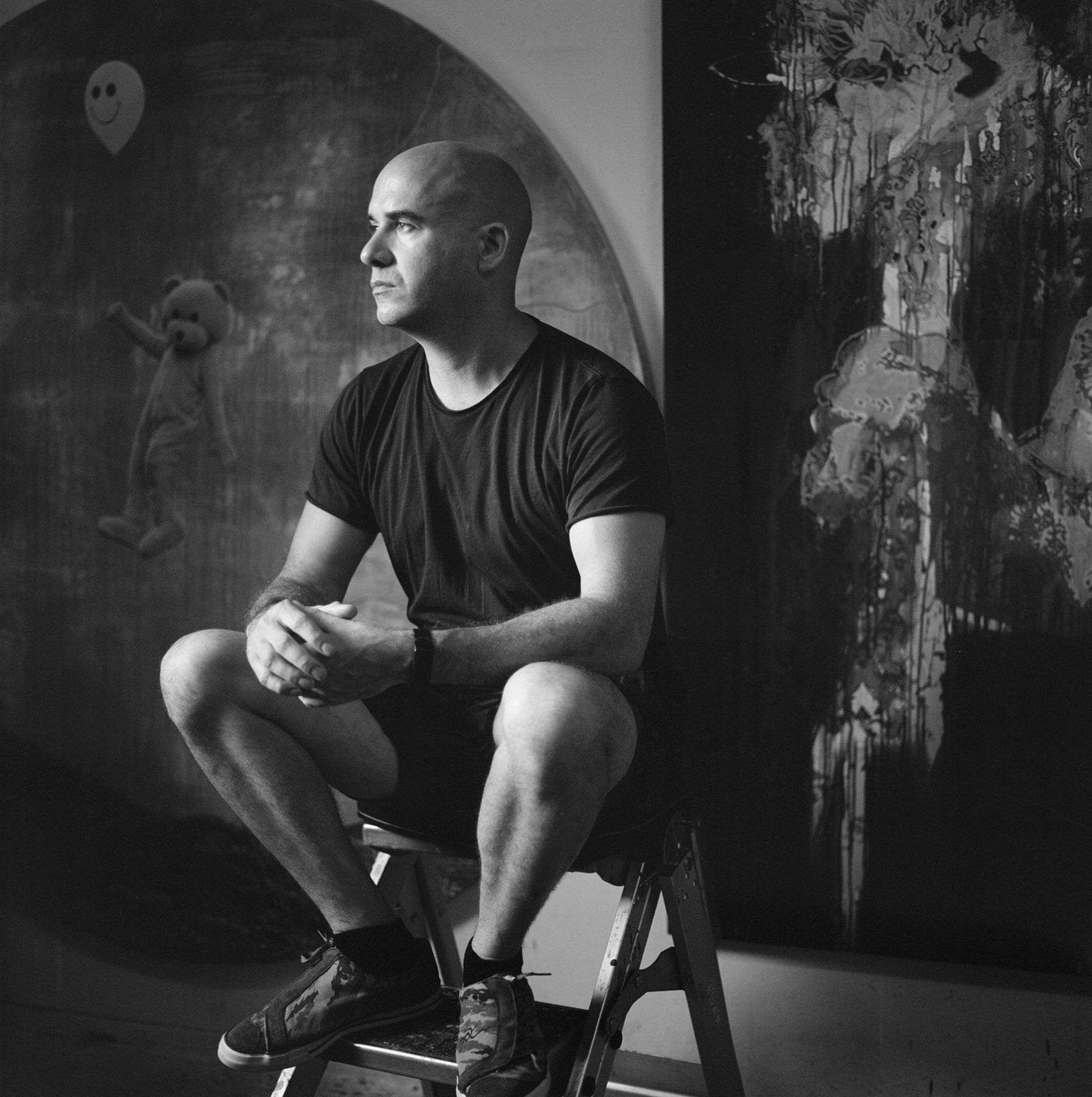 A man is sitting on a ladder in front of a painting
