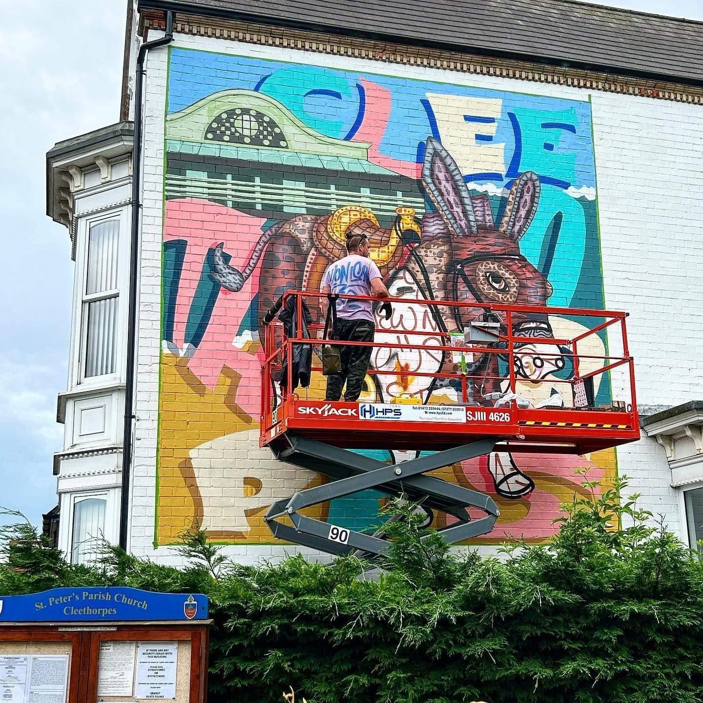 A man is painting a mural on the side of a building.
