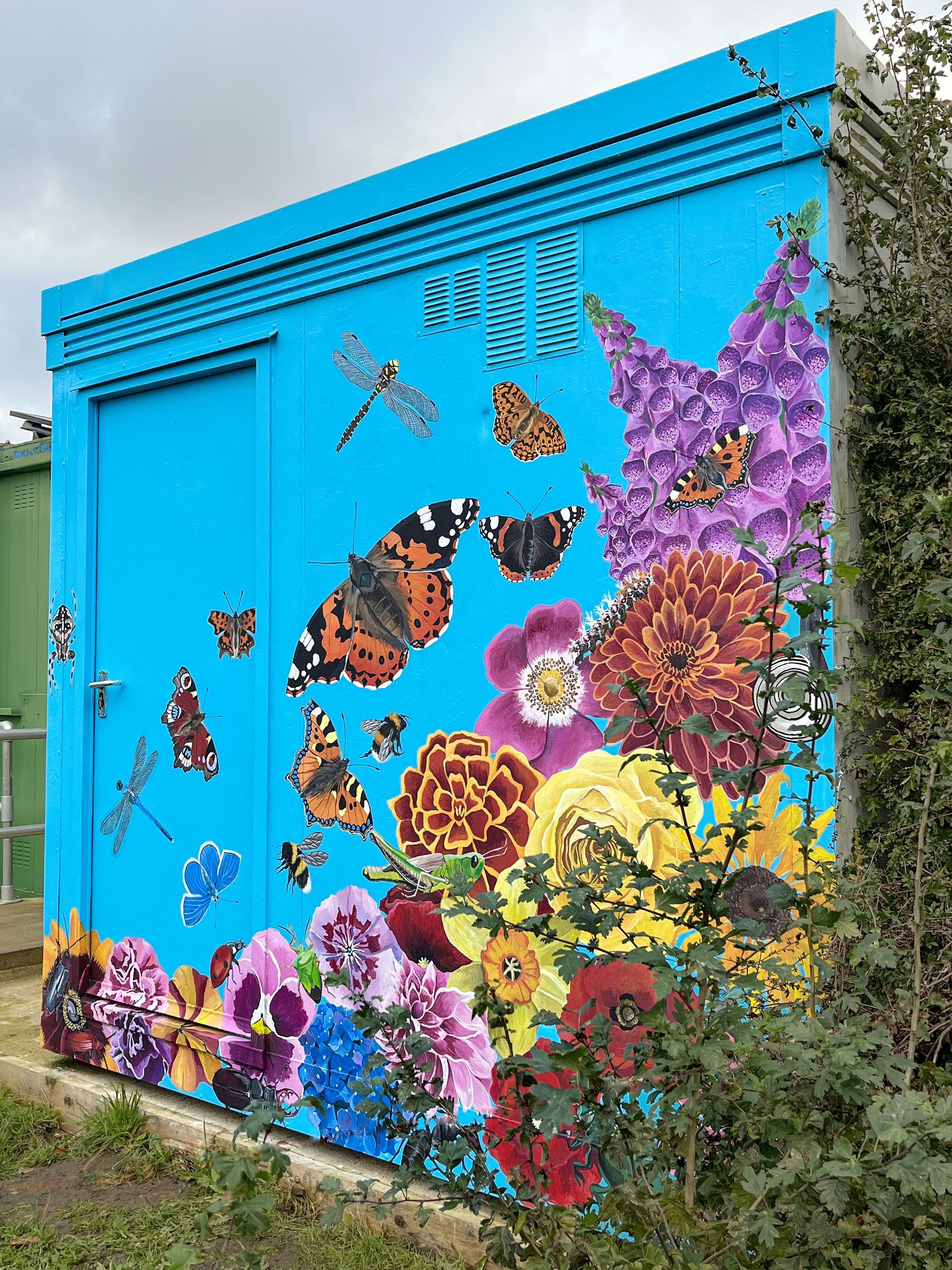 A blue building with a painting of butterflies and flowers on it.