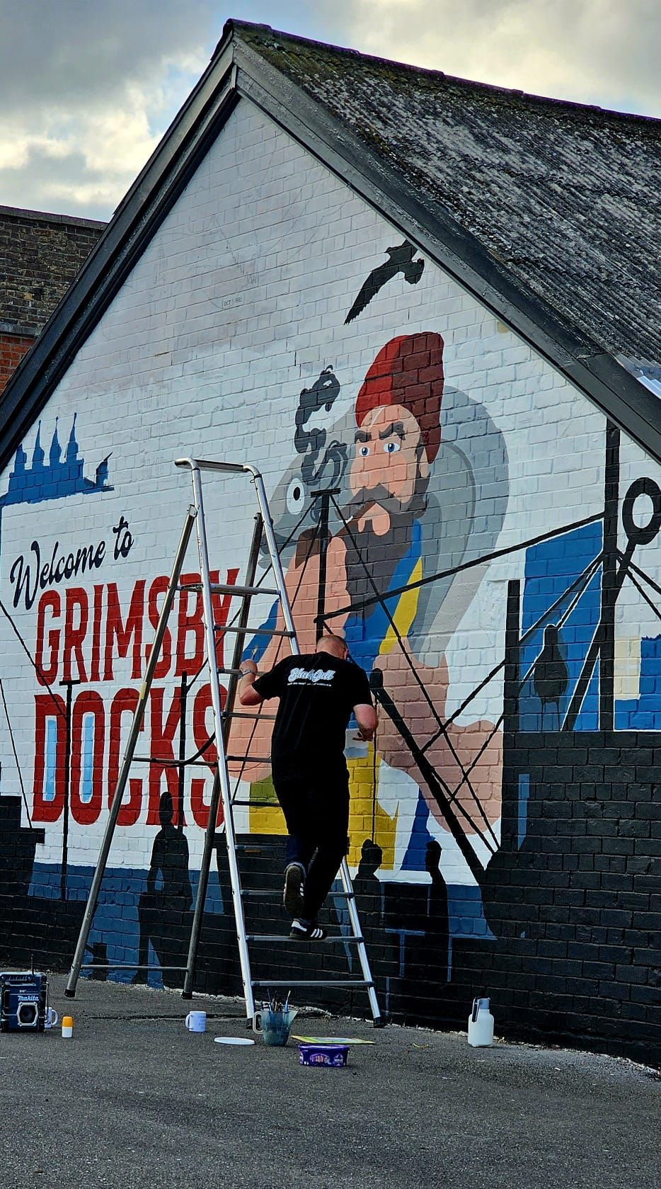 A man is painting a mural on the side of a building.