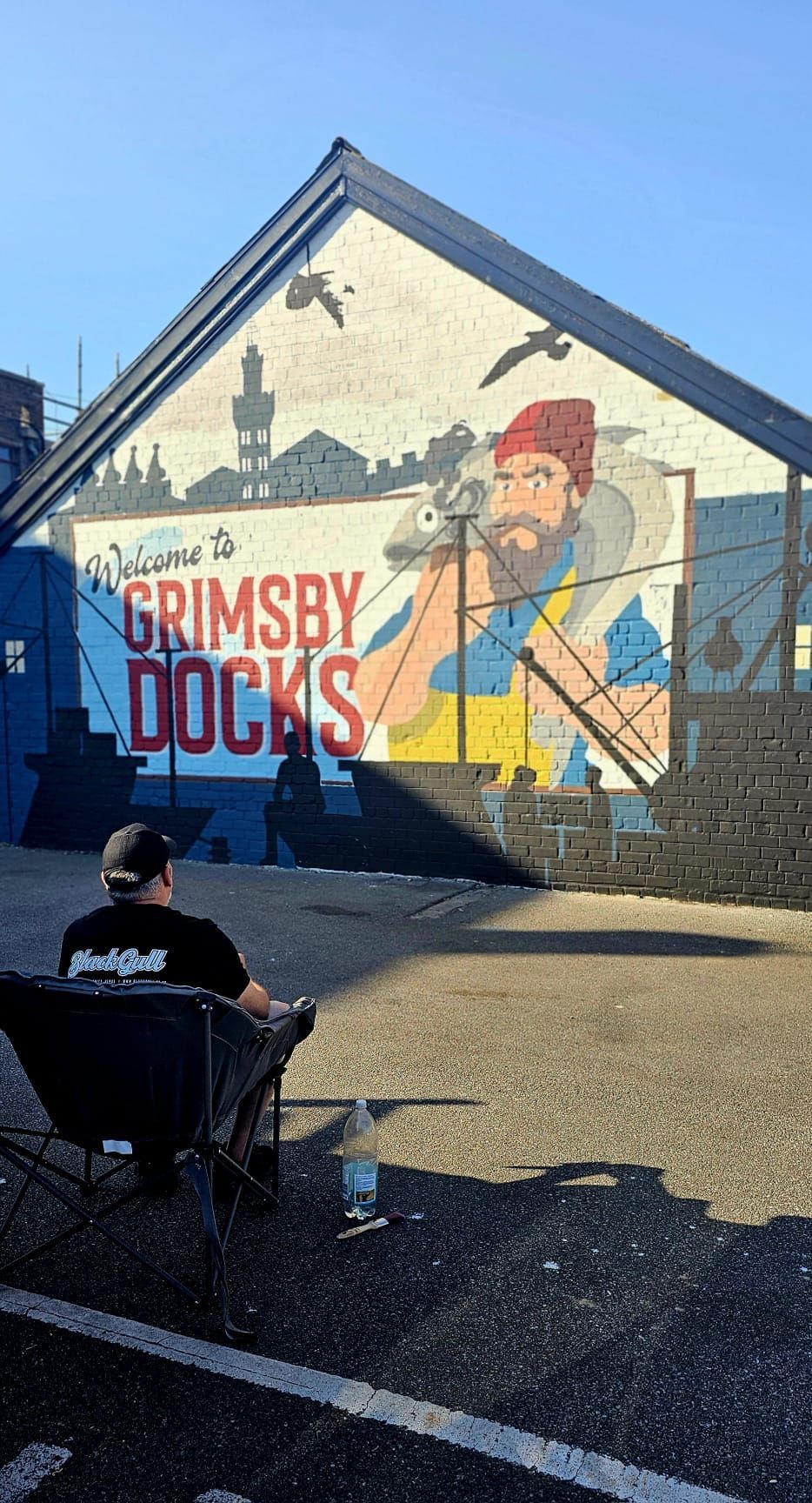 A man is sitting in a chair in front of a mural on the side of a building.