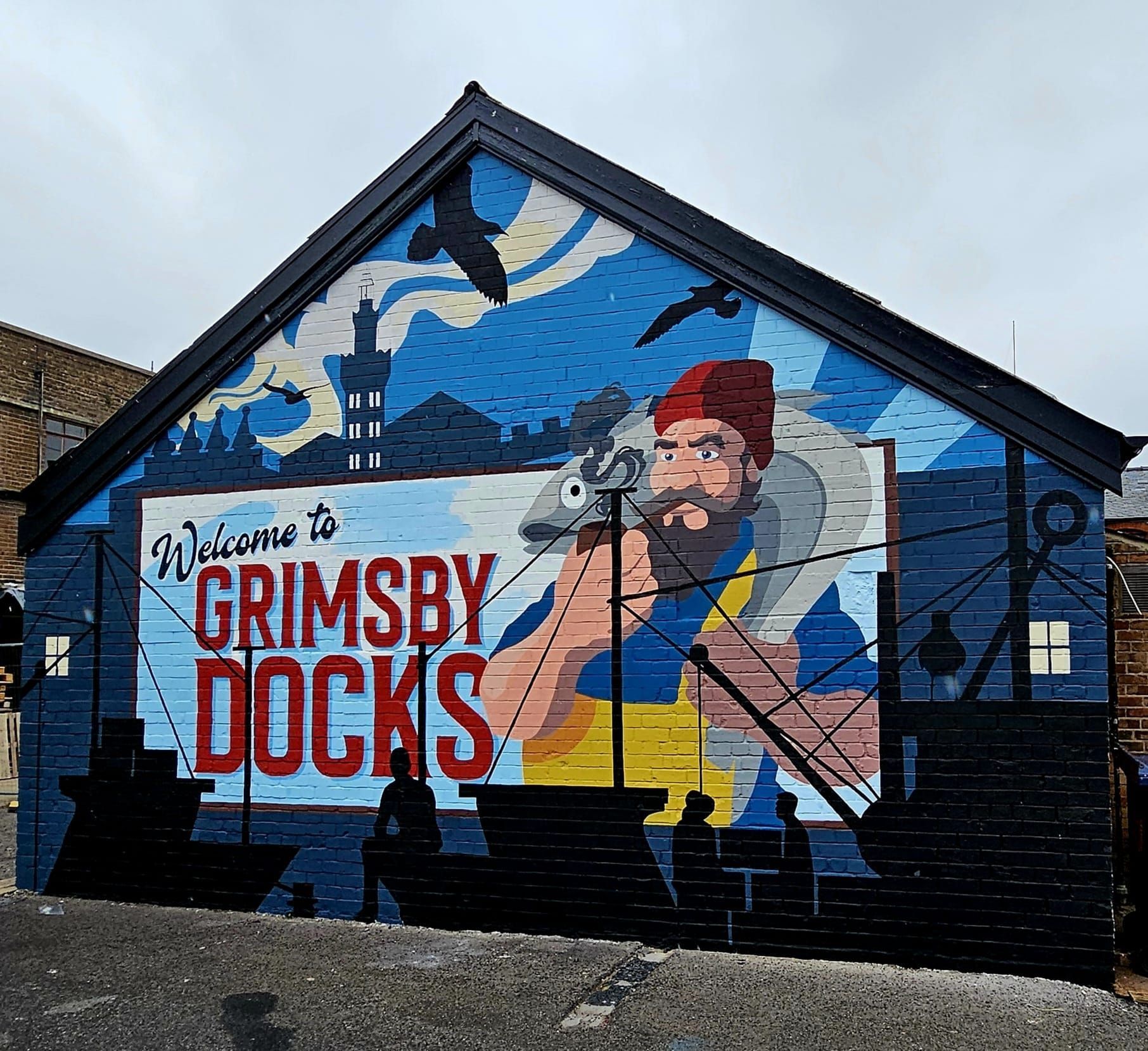 A mural on the side of a building welcomes people to grimsby docks