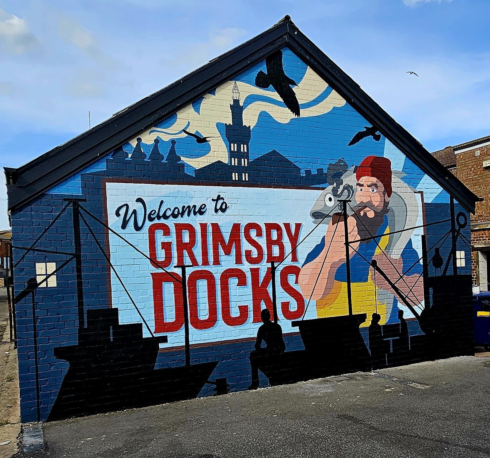 A mural on the side of a building welcomes people to grimsby docks