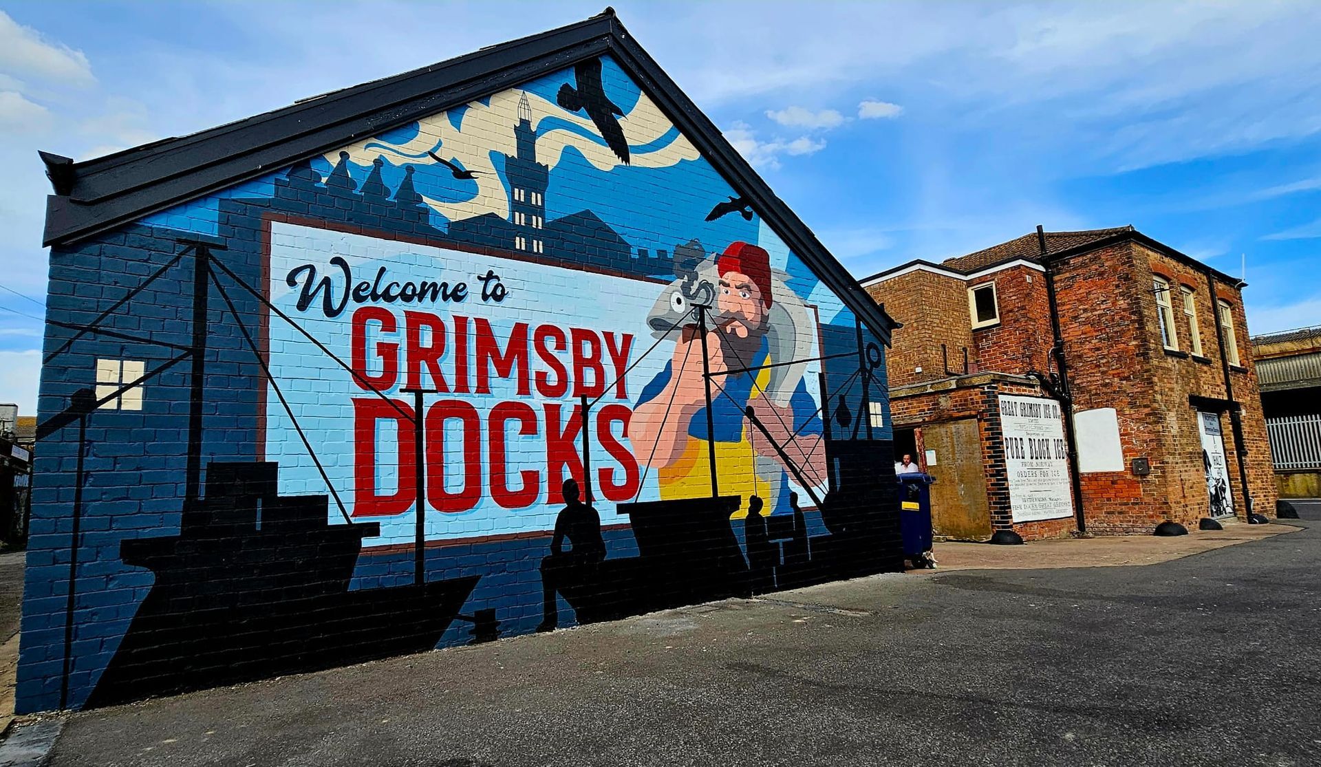 A mural on the side of a building that says welcome to grimsby docks