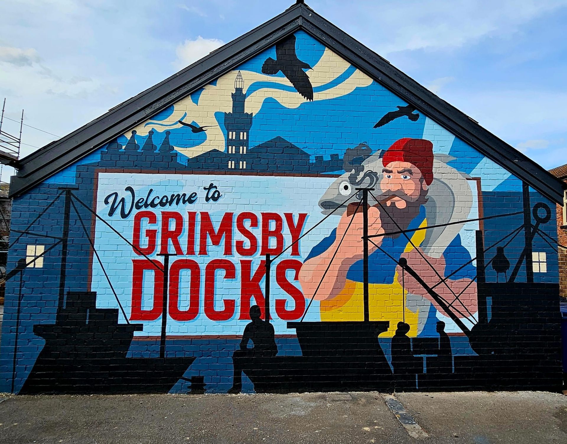 A mural on the side of a building welcomes people to grimsby docks