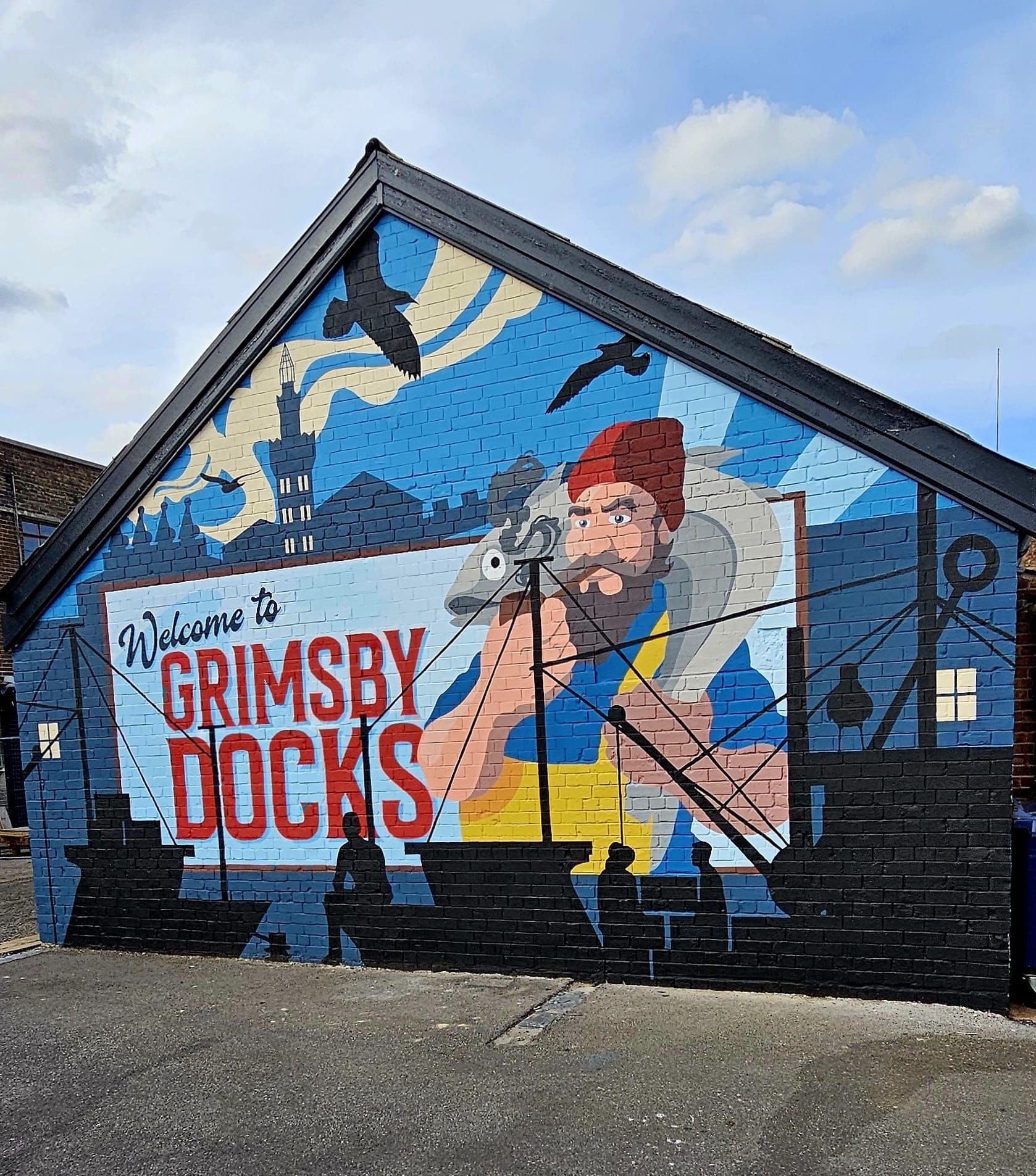 A mural on the side of a building that says welcome to grimsby docks