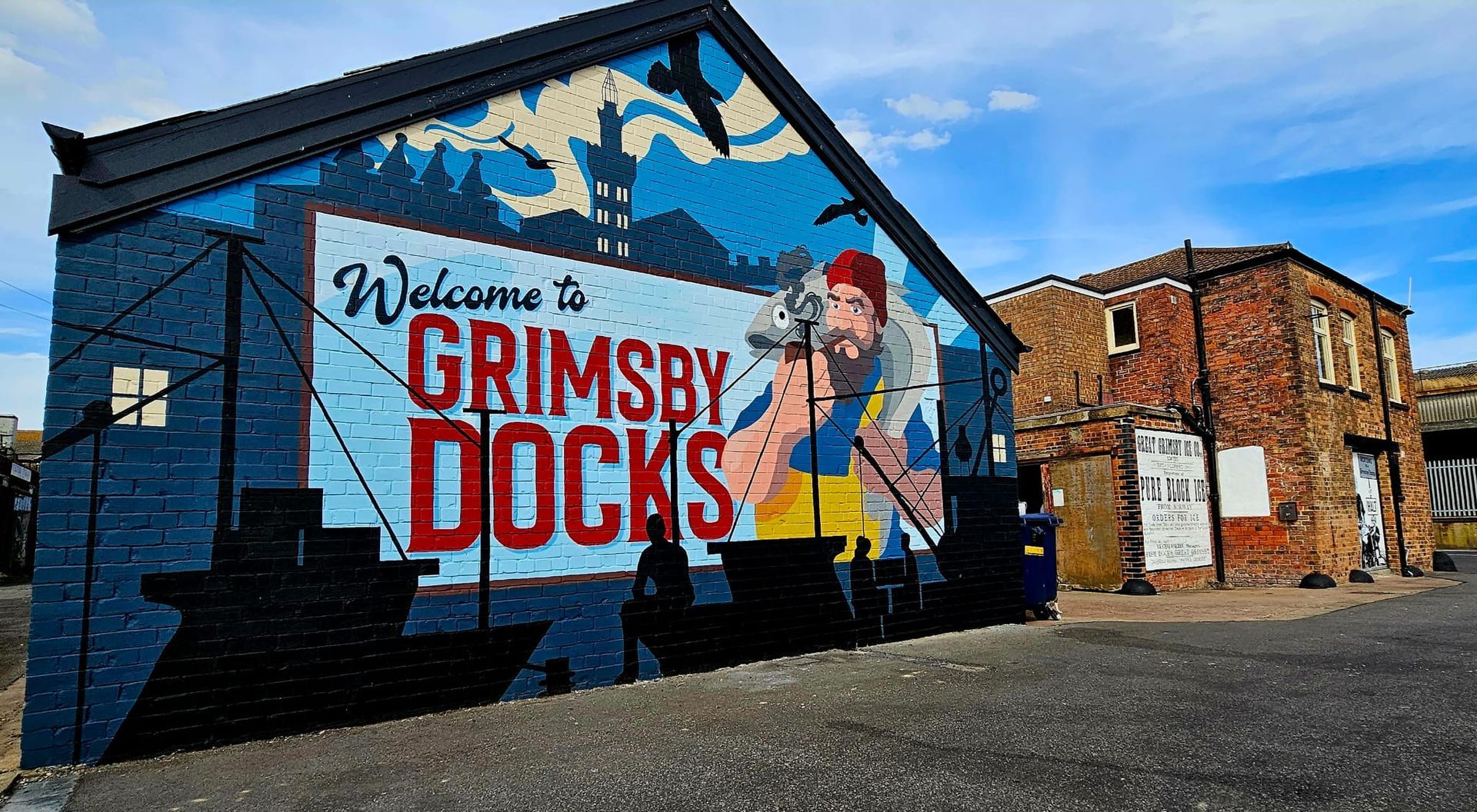 A large mural on the side of a building welcomes people to grimsby docks.