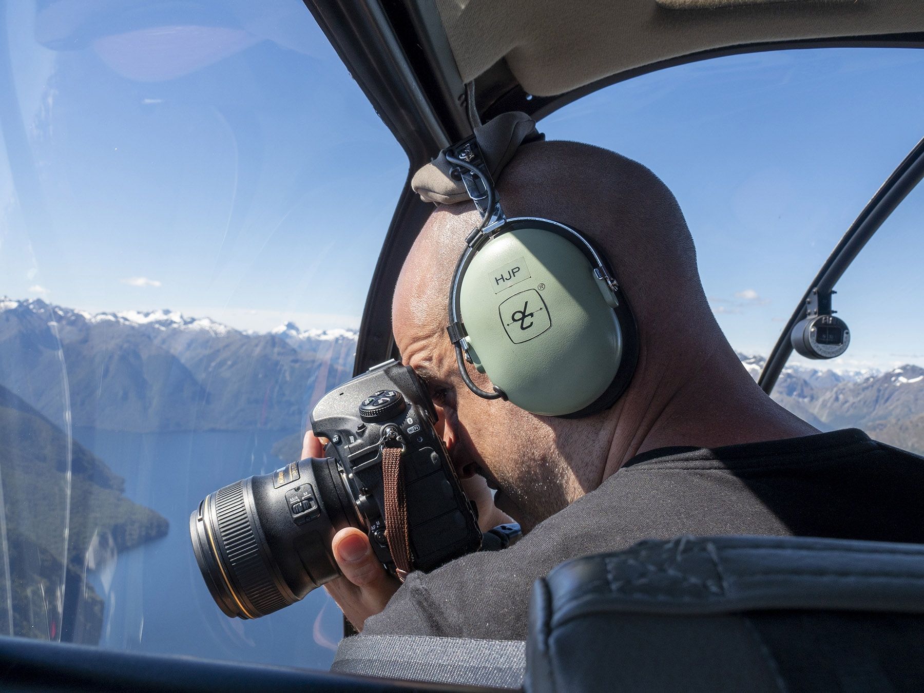 A man wearing headphones is taking a picture with a camera