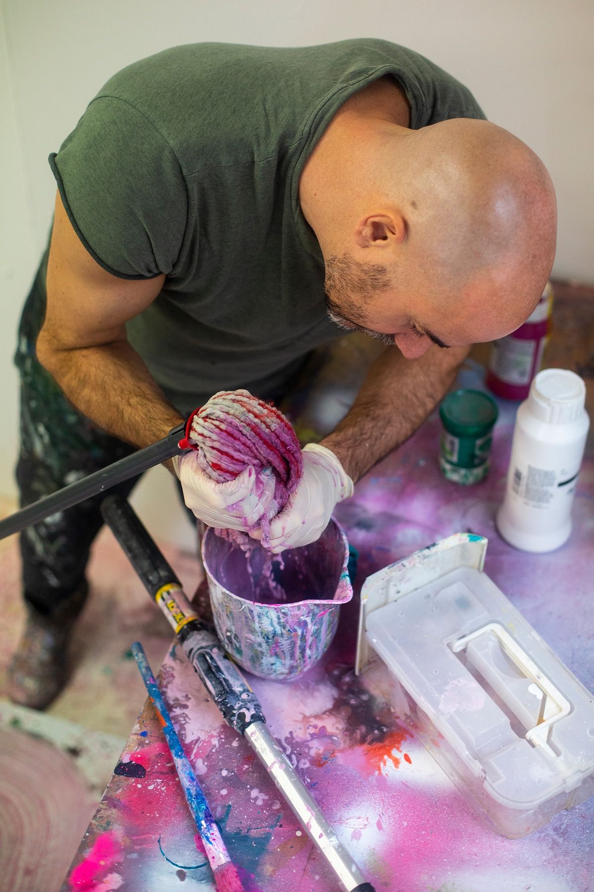A man is mixing paint in a bucket on a table.