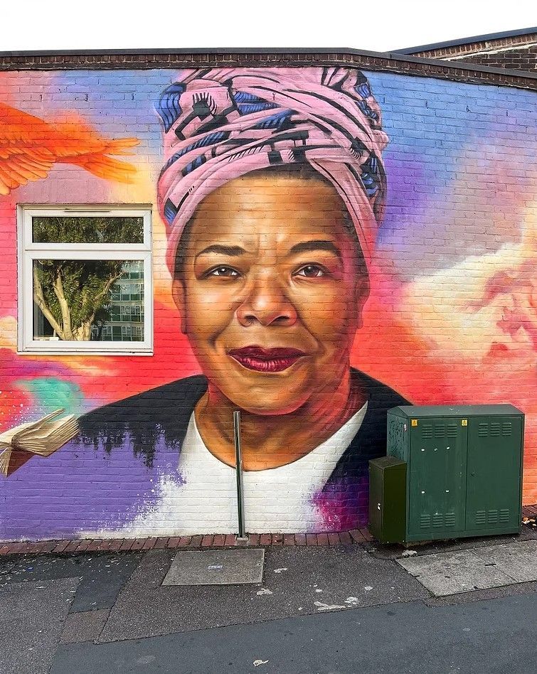 A mural of a woman wearing a pink turban on a brick wall.