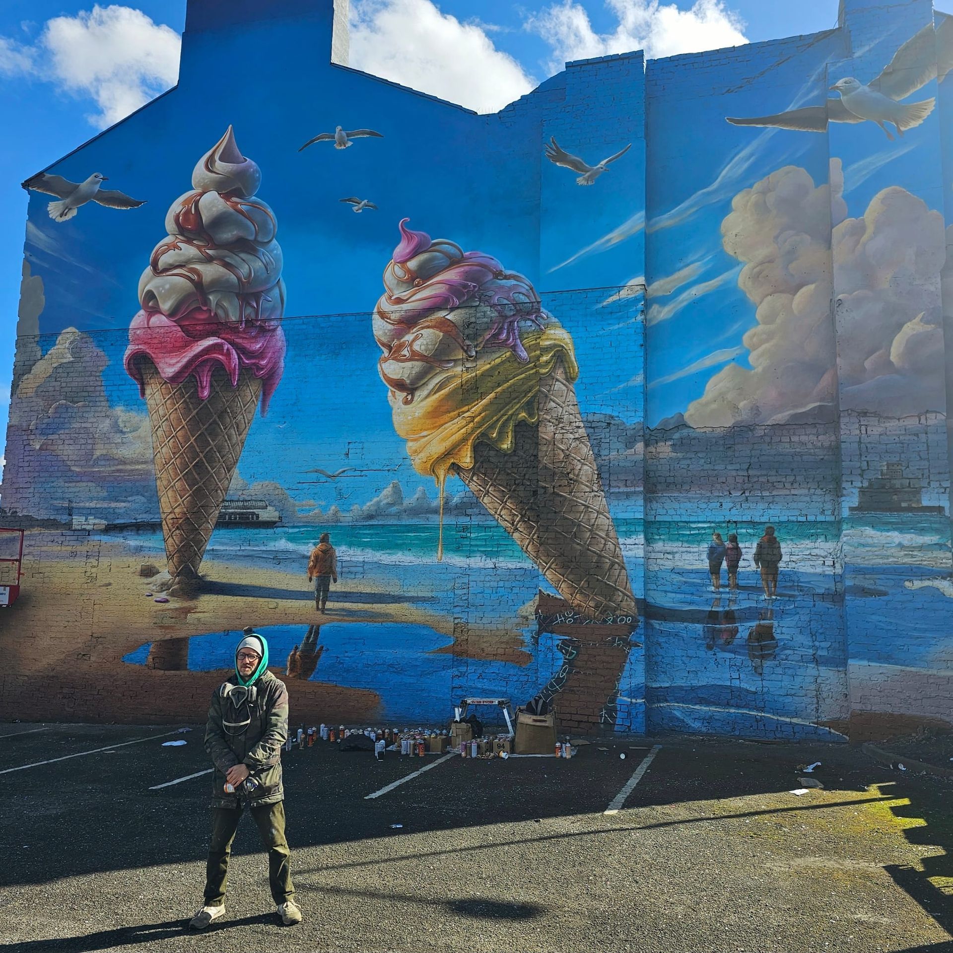 A man stands in front of a large mural of ice cream cones